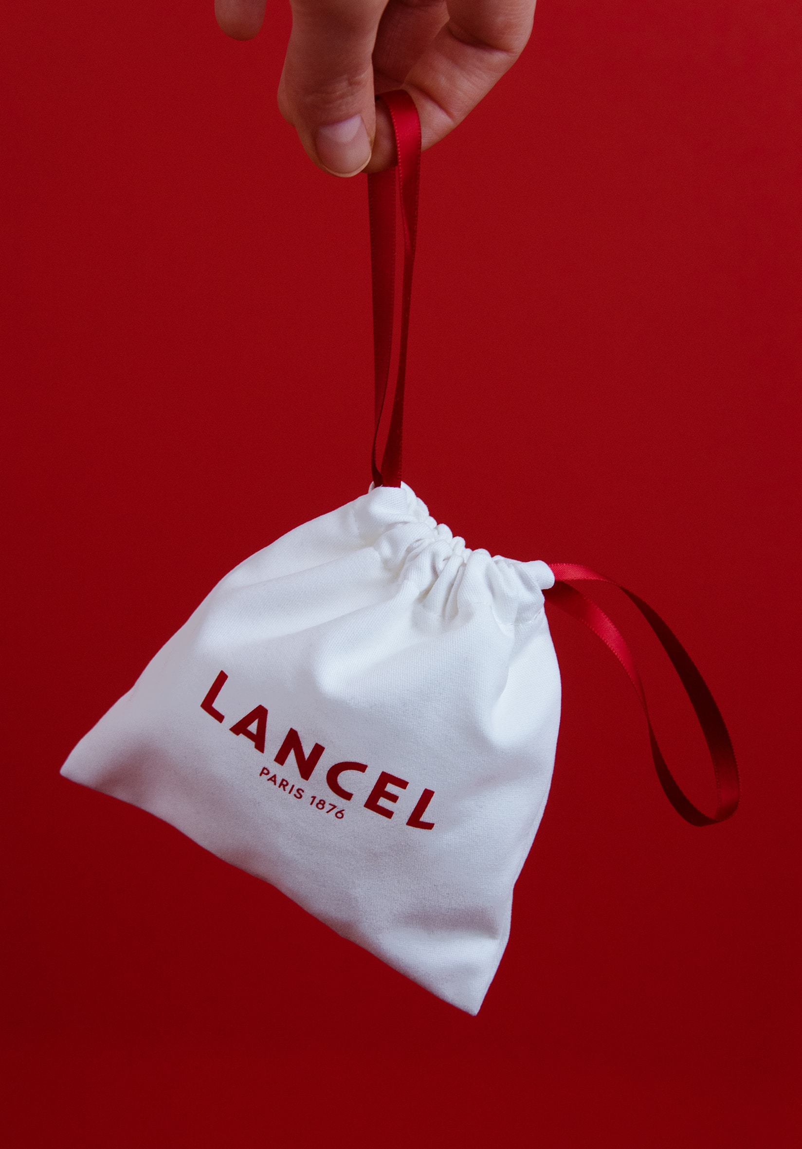 Pochon Lancel en coton blanc avec ruban rouge pour les petits produits.